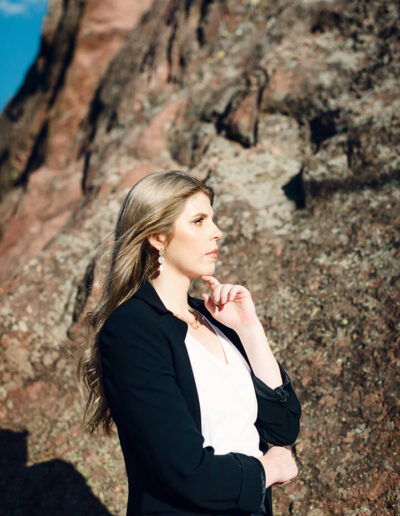 woman facing sideways outside by a rock wall