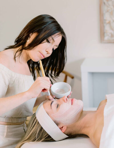 woman applying facial cream to a womans face