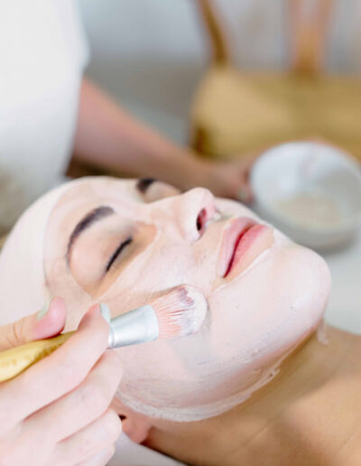woman applying facial cream to a womans face