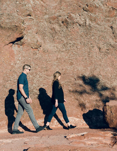 man and woman walking by rock formation